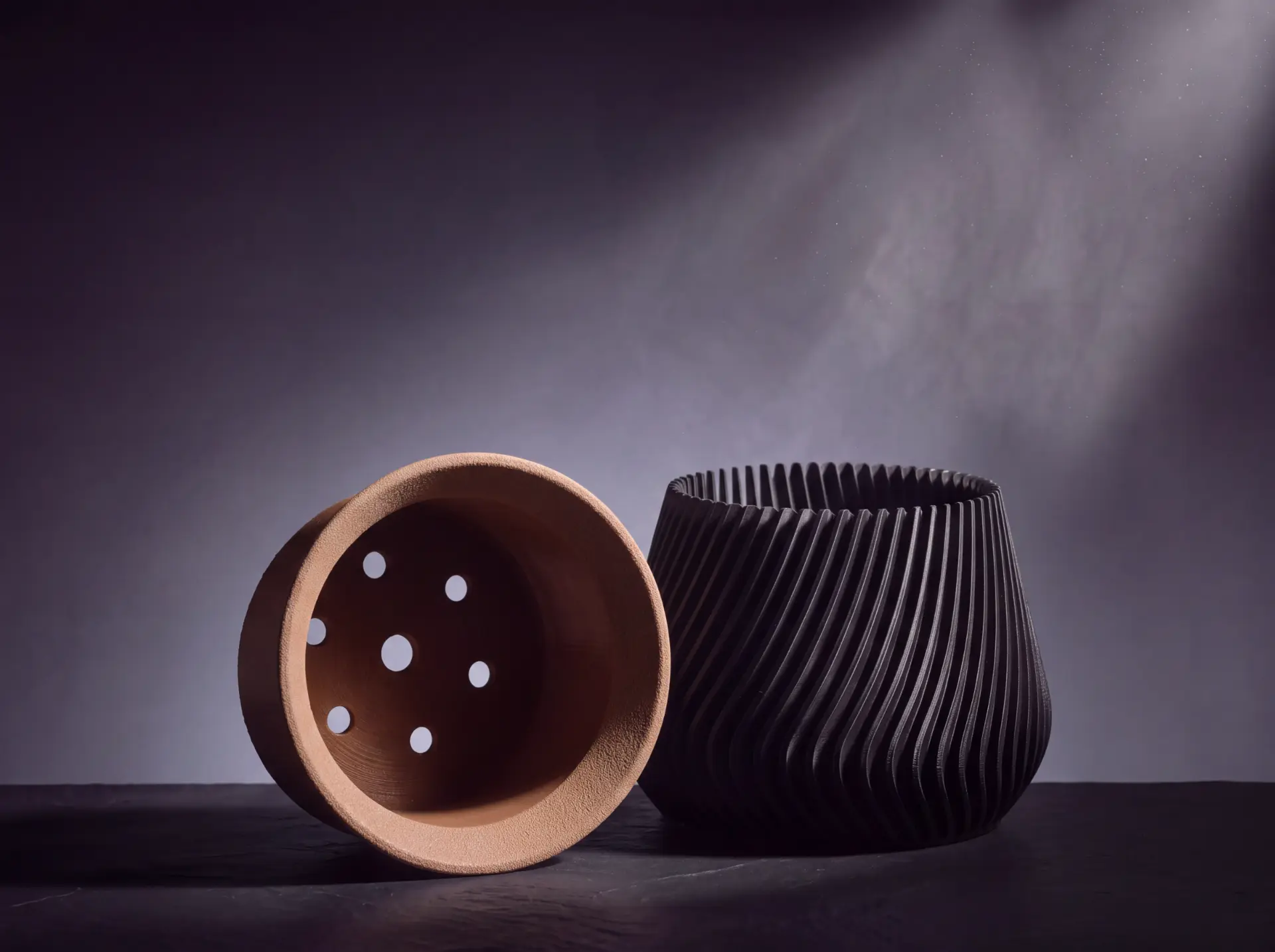 The inner container tipped forward to show the drainage holes in its base, next to the ribbed outer body.